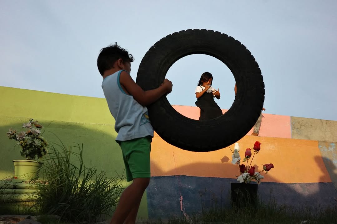 Artist Spotlight: “Catch A Moment” by @hersleyvencasero

This weeks Artist Spotlight features Hersley-Ven Casero, multidisciplinary visual artist and photographer based in Dumaguete City, Philippines. His long-term series, “Catch A Moment” moves through everyday streets and fleeting glances, finding honesty in the uncanny moments that make us deeply human.

“These photographs are not about perfection. They are about presence. I’m chasing a feeling: the rush of kids mid-air above the sea, the hush of light falling through a window, a dog silhouetted against a golden sky, kids playing atop sacks of crimson onions, glowing like jewels, a woman’s face caught twice in one moment, real and reflected. Every frame is a quiet witnessing, a heartbeat stilled in time.

Drawn to the poetry of the everyday, I look for the magic in the mundane: in the warmth of sunlit walls, in shadows cast by strangers, in the choreography of street life unfolding without warning. This is where stories live, where life pulses loudest in its smallest, most honest gestures.

Catch A Moment is my way of honoring what most might walk past. It is not about capturing the perfect shot. It is about capturing the true one, the kind that stirs something in you, the kind you feel before you fully see.”