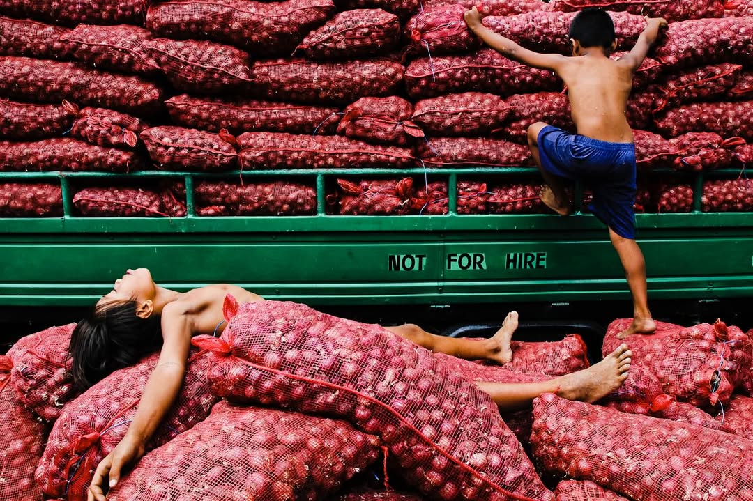 Artist Spotlight: “Catch A Moment” by @hersleyvencasero

This weeks Artist Spotlight features Hersley-Ven Casero, multidisciplinary visual artist and photographer based in Dumaguete City, Philippines. His long-term series, “Catch A Moment” moves through everyday streets and fleeting glances, finding honesty in the uncanny moments that make us deeply human.

“These photographs are not about perfection. They are about presence. I’m chasing a feeling: the rush of kids mid-air above the sea, the hush of light falling through a window, a dog silhouetted against a golden sky, kids playing atop sacks of crimson onions, glowing like jewels, a woman’s face caught twice in one moment, real and reflected. Every frame is a quiet witnessing, a heartbeat stilled in time.

Drawn to the poetry of the everyday, I look for the magic in the mundane: in the warmth of sunlit walls, in shadows cast by strangers, in the choreography of street life unfolding without warning. This is where stories live, where life pulses loudest in its smallest, most honest gestures.

Catch A Moment is my way of honoring what most might walk past. It is not about capturing the perfect shot. It is about capturing the true one, the kind that stirs something in you, the kind you feel before you fully see.”