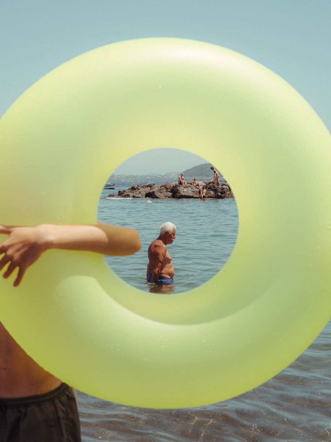 ‘A Frame From The Italian Seaside,’ as seen through Copenhagen-based photographer Anna Landstedt’s (@annalandstedt) camera. Often working on the move, Anna’s images are transportive in nature, capturing the essence of coastal life in instances where light, color, and atmosphere merge to shape an experience.
“Taken on Ischia, this moment came together without much control. A split second, a frame within a frame. The beach was loud, full of movement and noise: kids playing, families gathered around food, sandy fingers and that sweet smell of sticky sunscreen. In the midst of it all, he stood still in the cool water. A frame within a frame, an oasis in the chaos.”