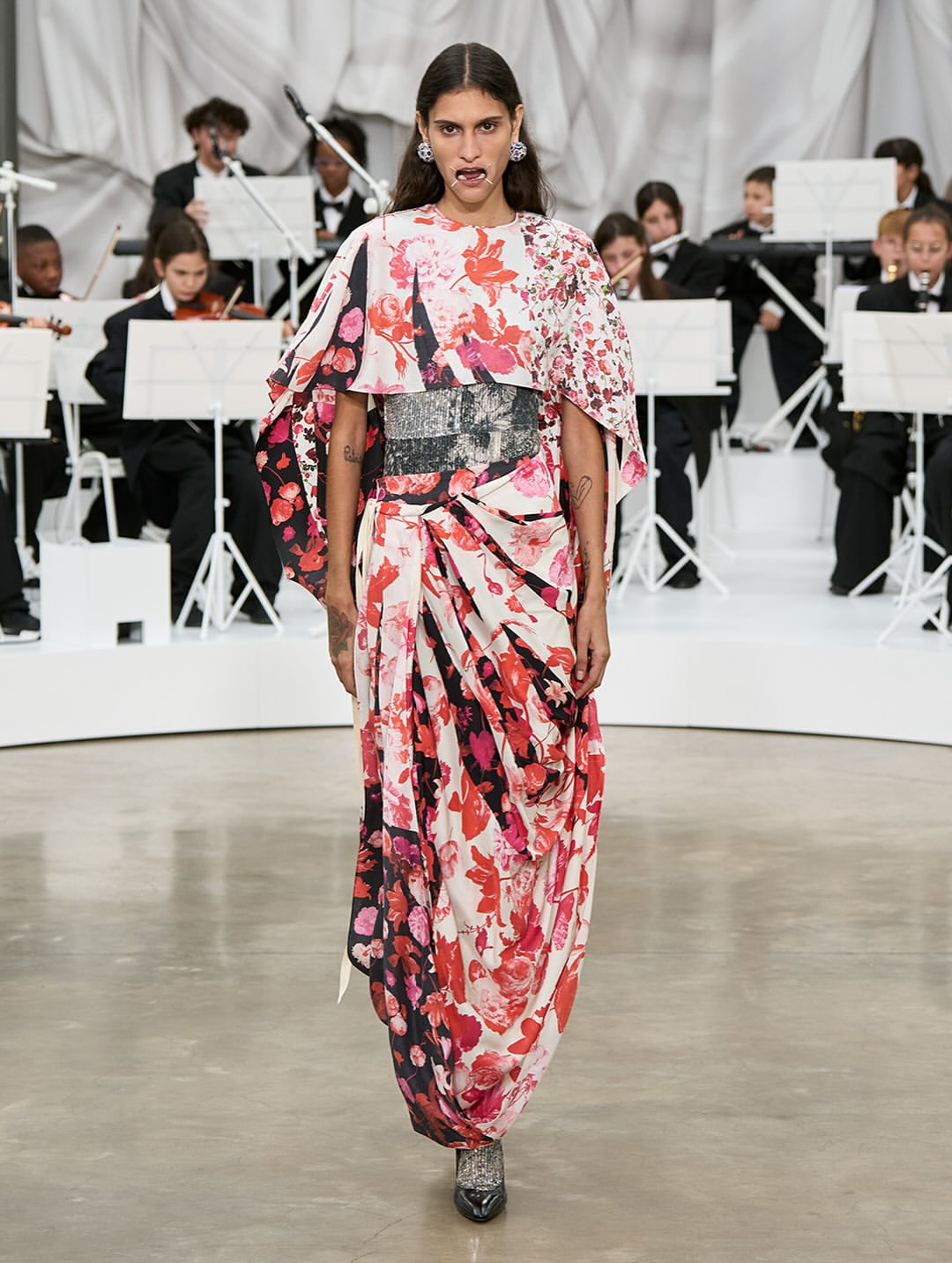 Maison Margiela Co-Ed SS26, Paris Fashion Week

At the recent Paris Fashion Week, Glenn Martens revealed his first ready-to-wear collection for Maison Margiela, following his debut at the Haute Couture show last July.
The collection immediately made an impression, notably with the four metal bars that stretched the models’ mouths, reminiscent of dental retractors, yet shaped in the brand’s iconic Four Stitches motif.
Tailoring was reinvented this season with innovative shoulder constructions, ultra-low-rise trousers, and jackets with tie closures. The runway also showcased striking textures: 16th-century floral wallpaper prints recreated on knitwear, tops made from fused and recycled vintage jewelry, silk jackets and coats fully coated in plastic for a waterproof effect, knitted plastic fabrics, and corsets and shoulder details on certain dresses.
For his debut show, Glenn Martens offered “fresh design ideas alongside reimagined and evolved pieces from the archives, crafted by the entire Maison Margiela team.”

Creative Direction @maisonmargiela @glennmartens
Styling @ursinagysi
Make Up @ingegrognard
Hair @garygillhair
Nails @cam.t.artist
Backstage Photographer @melanie_ramon 
Post House @sheriff.projects
#sheriffprojects