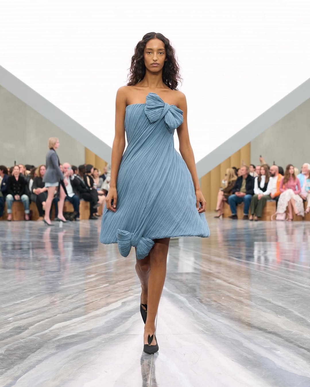 Dior SS26, Paris Fashion Week

During the latest Paris Fashion Week, Jonathan Anderson unveiled his first womenswear collection for Dior. The show opened with an Adam Curtis–directed short film projected on a pyramidal screen, tracing Dior’s creative legacy, from Christian Dior’s floral silhouettes to Galliano’s theatrical flair, while paying homage to Maria Grazia Chiuri’s artistic influence.
Models appeared from behind an open Dior archival box, wearing reimagined classics infused with Anderson’s postmodern, surreal touch. The opening look, a white dress echoing Dior’s 1952 “Cigale” design, set the tone with exaggerated bows and sculptural shapes. Throughout, Anderson intertwined his own aesthetic with the house’s heritage, blending historical drama with contemporary edge: peplum blazers paired with frayed denim, transparent gowns over nude bodysuits, and voluminous caban coats. Stephen Jones’s origami hats and rose-toe shoes completed a collection that elegantly bridged Dior’s past and Anderson’s avant-garde vision.

Creative Direction @dior @jonathan.anderson
Styling @benjaminbruno_
Make Up @peterphilipsmakeup
Hair @guidopalau
Backstage Photographer @mireia_deulofeu
Post House @sheriff.projects
#sheriffprojects