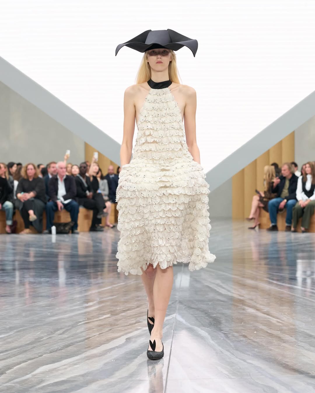 Dior SS26, Paris Fashion Week

During the latest Paris Fashion Week, Jonathan Anderson unveiled his first womenswear collection for Dior. The show opened with an Adam Curtis–directed short film projected on a pyramidal screen, tracing Dior’s creative legacy, from Christian Dior’s floral silhouettes to Galliano’s theatrical flair, while paying homage to Maria Grazia Chiuri’s artistic influence.
Models appeared from behind an open Dior archival box, wearing reimagined classics infused with Anderson’s postmodern, surreal touch. The opening look, a white dress echoing Dior’s 1952 “Cigale” design, set the tone with exaggerated bows and sculptural shapes. Throughout, Anderson intertwined his own aesthetic with the house’s heritage, blending historical drama with contemporary edge: peplum blazers paired with frayed denim, transparent gowns over nude bodysuits, and voluminous caban coats. Stephen Jones’s origami hats and rose-toe shoes completed a collection that elegantly bridged Dior’s past and Anderson’s avant-garde vision.

Creative Direction @dior @jonathan.anderson
Styling @benjaminbruno_
Make Up @peterphilipsmakeup
Hair @guidopalau
Backstage Photographer @mireia_deulofeu
Post House @sheriff.projects
#sheriffprojects